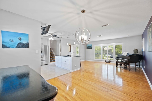 interior space with ceiling fan with notable chandelier and light wood-type flooring