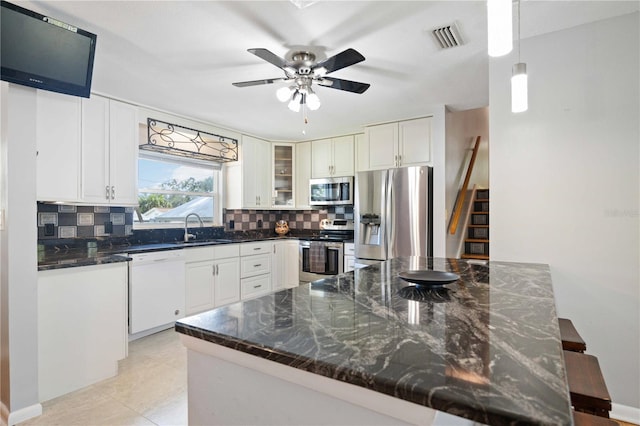 kitchen featuring backsplash, white cabinetry, hanging light fixtures, and stainless steel appliances