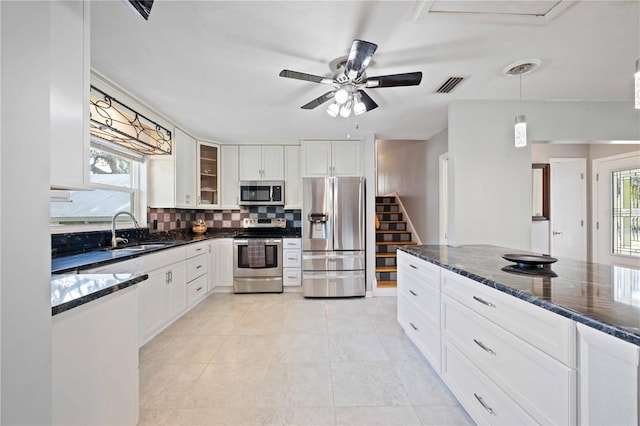 kitchen with pendant lighting, sink, dark stone countertops, white cabinetry, and stainless steel appliances