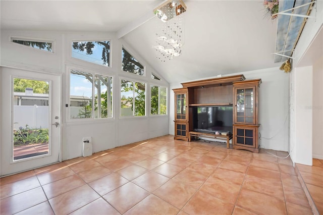 unfurnished living room featuring a wealth of natural light, light tile patterned floors, high vaulted ceiling, and a notable chandelier