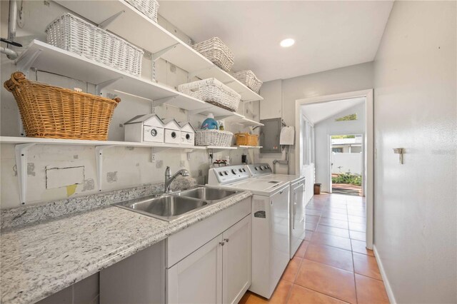 kitchen featuring light stone countertops, sink, washer and dryer, white cabinets, and light tile patterned flooring