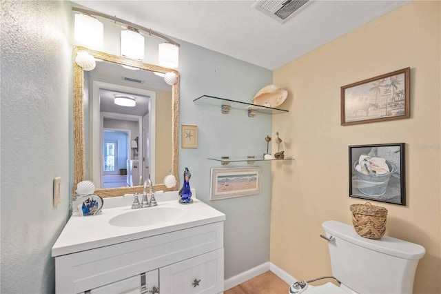 bathroom featuring vanity, a textured ceiling, and toilet