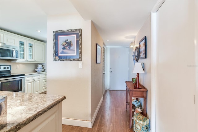 kitchen with white cabinets, light hardwood / wood-style flooring, stainless steel appliances, and light stone countertops