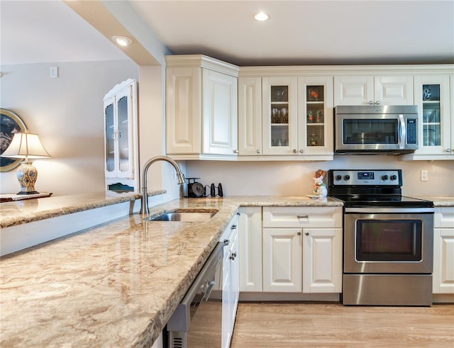 kitchen featuring appliances with stainless steel finishes, light hardwood / wood-style flooring, sink, and white cabinets