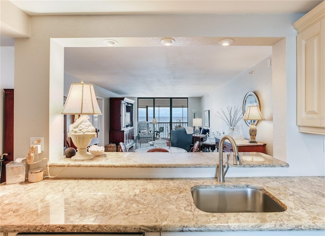 kitchen featuring floor to ceiling windows, sink, and light stone countertops