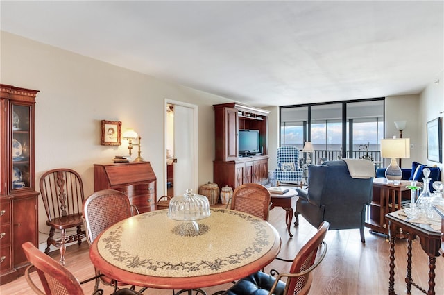 dining space with expansive windows and light hardwood / wood-style floors