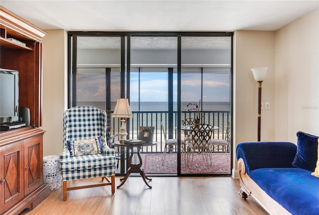 sitting room with a water view, hardwood / wood-style floors, and floor to ceiling windows