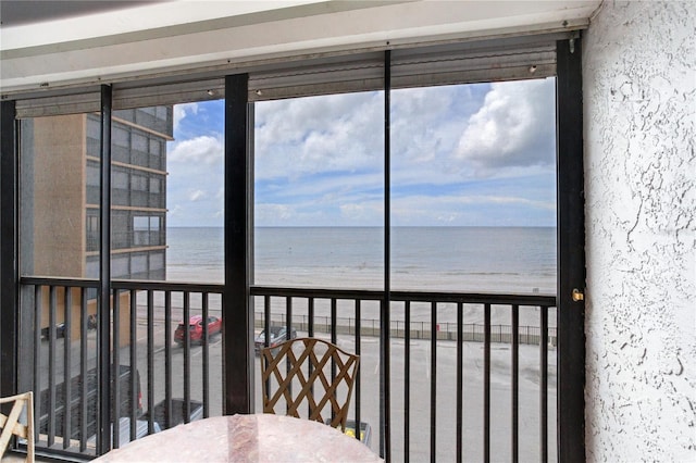 unfurnished sunroom featuring a water view, a view of the beach, and a wealth of natural light