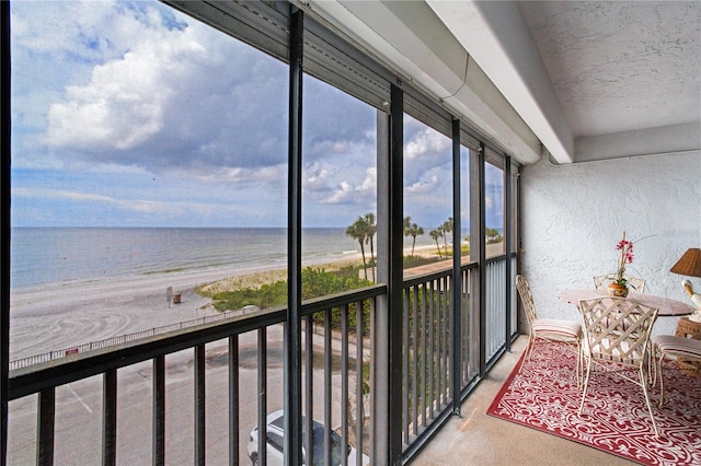 sunroom / solarium with a beach view and a water view