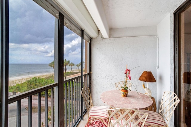 balcony featuring a water view and a beach view