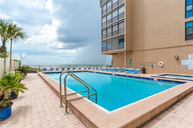 view of pool featuring a hot tub and a water view