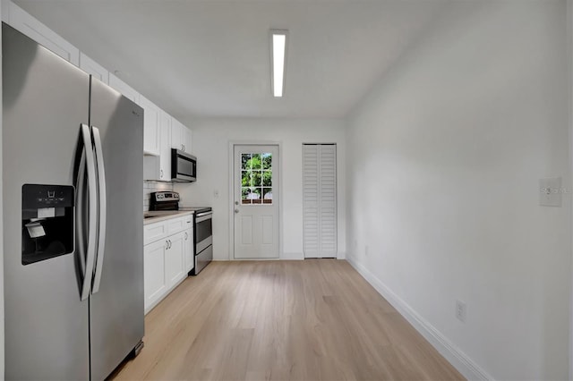 kitchen with appliances with stainless steel finishes, backsplash, light hardwood / wood-style flooring, and white cabinets