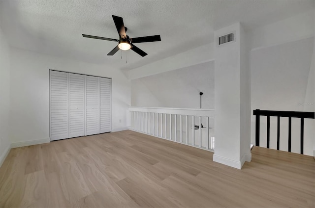 interior space with ceiling fan, a textured ceiling, and light hardwood / wood-style floors