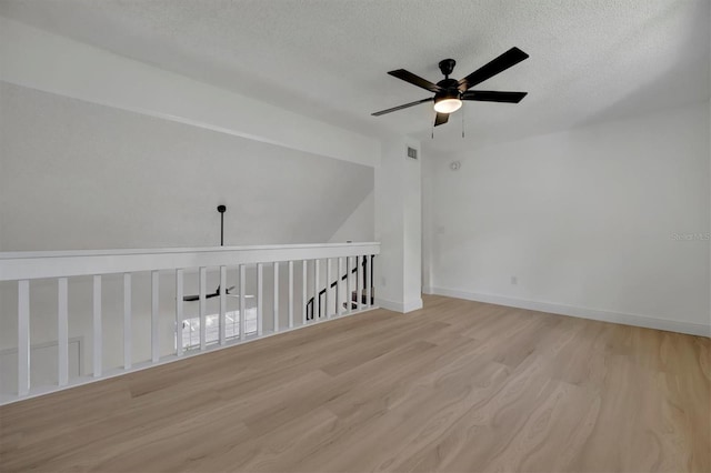 empty room featuring light wood-type flooring, ceiling fan, and a textured ceiling