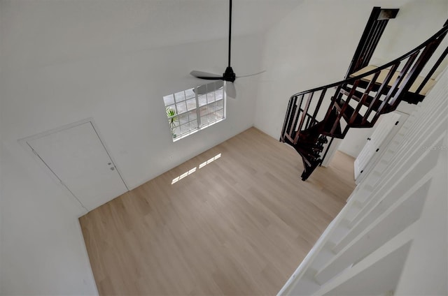 stairs with a towering ceiling, hardwood / wood-style flooring, and ceiling fan