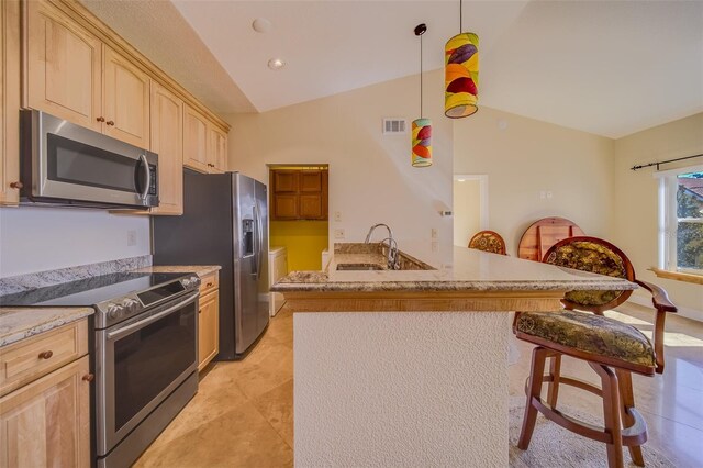 kitchen with decorative light fixtures, stainless steel appliances, lofted ceiling, light brown cabinets, and a breakfast bar area