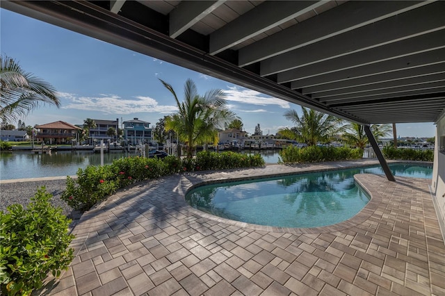 outdoor pool featuring a water view and a patio