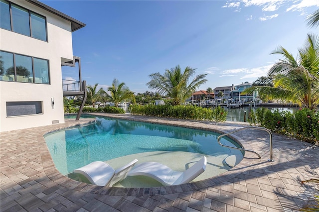 pool featuring a patio area and a water view