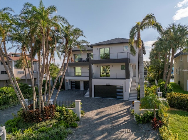 view of front of property with a garage, a balcony, stairs, decorative driveway, and stucco siding