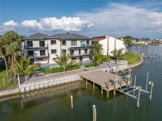 view of dock featuring a water view, an outdoor pool, boat lift, and a balcony