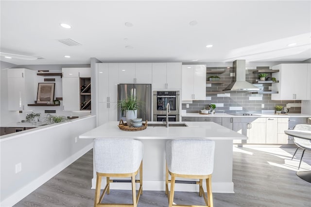 kitchen with open shelves, appliances with stainless steel finishes, a sink, modern cabinets, and wall chimney exhaust hood