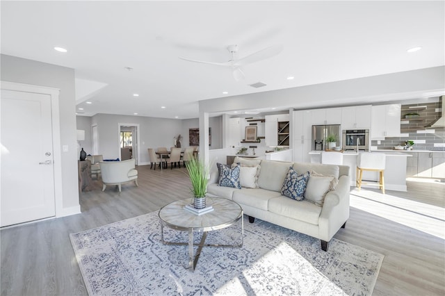 living room featuring a ceiling fan, recessed lighting, light wood-style flooring, and baseboards