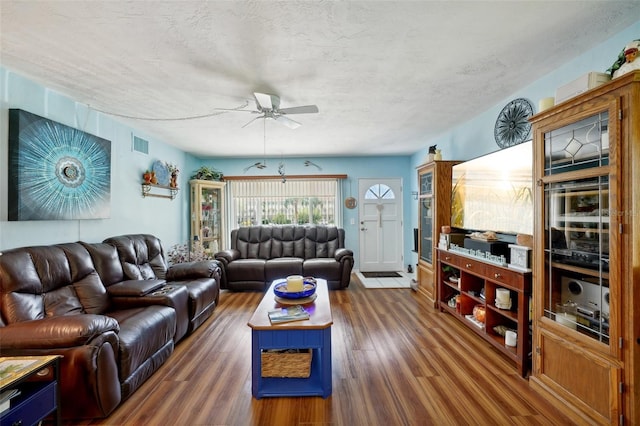 living room featuring ceiling fan, dark hardwood / wood-style floors, and a textured ceiling