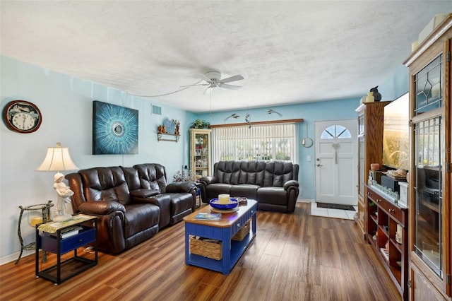 living room with a textured ceiling, ceiling fan, and dark hardwood / wood-style floors