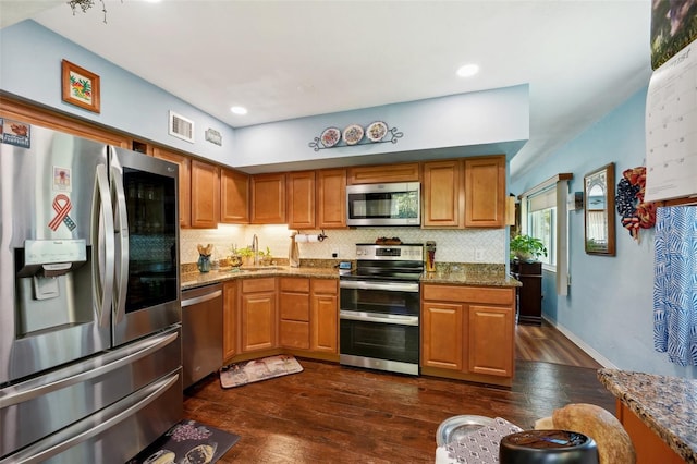 kitchen with appliances with stainless steel finishes, stone countertops, sink, dark hardwood / wood-style floors, and decorative backsplash