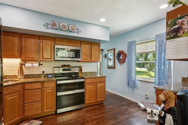 kitchen featuring backsplash, dark hardwood / wood-style floors, appliances with stainless steel finishes, and dark stone counters