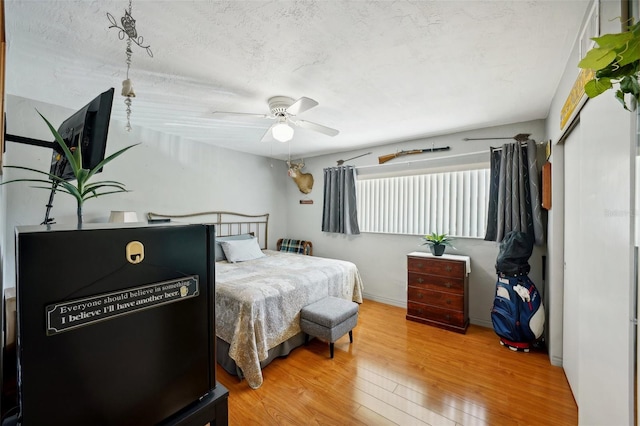 bedroom with a textured ceiling, hardwood / wood-style floors, and ceiling fan