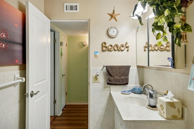 bathroom with tile walls, hardwood / wood-style floors, tasteful backsplash, and vanity