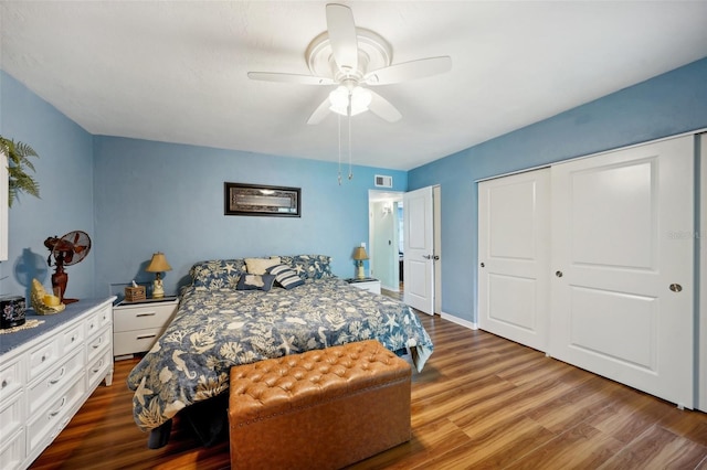 bedroom with dark wood-type flooring, ceiling fan, and a closet