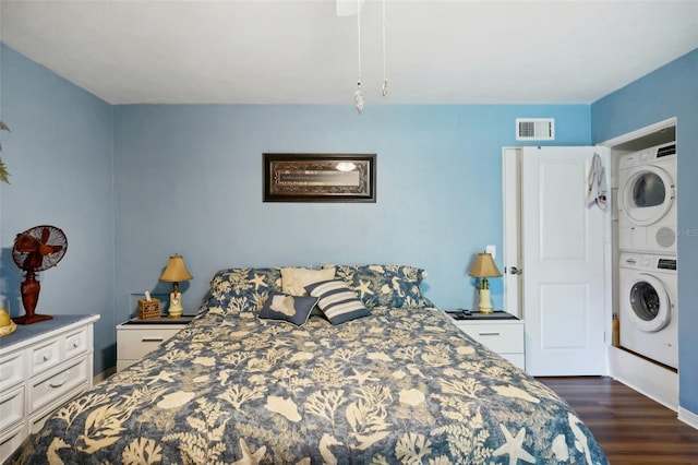 bedroom with stacked washer and dryer and dark hardwood / wood-style flooring