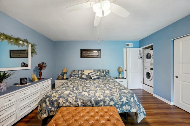 bedroom featuring stacked washing maching and dryer, ceiling fan, and dark hardwood / wood-style floors