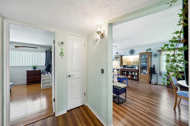 corridor with a textured ceiling and dark hardwood / wood-style floors