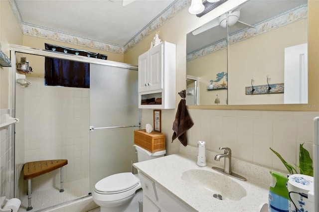 bathroom with toilet, vanity, backsplash, tile walls, and a shower with shower door