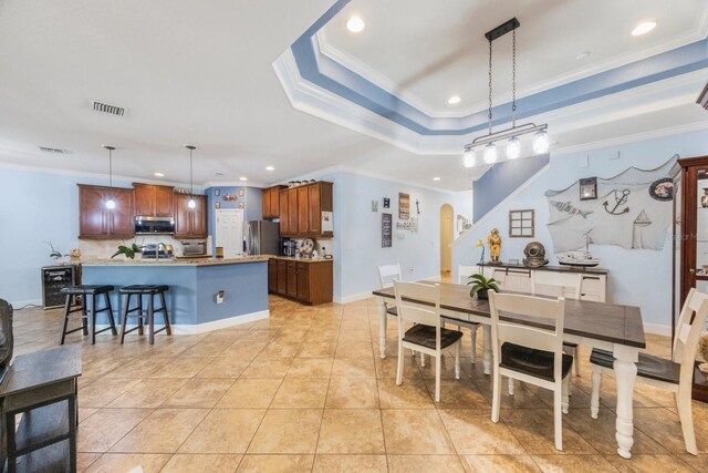 tiled dining area featuring crown molding and a tray ceiling