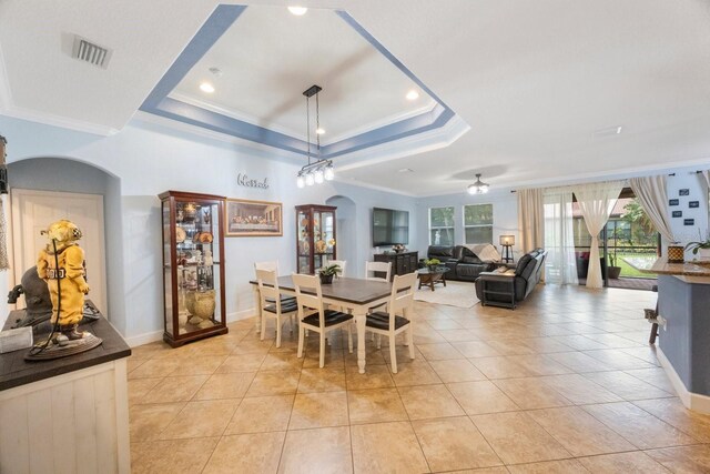 tiled dining room with a wealth of natural light, a tray ceiling, and ceiling fan