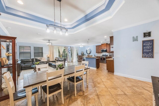 tiled dining room with ornamental molding and a tray ceiling