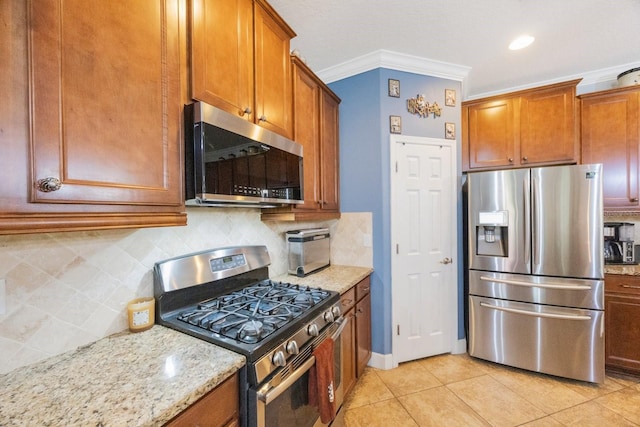 kitchen with crown molding, light tile patterned flooring, appliances with stainless steel finishes, light stone counters, and tasteful backsplash