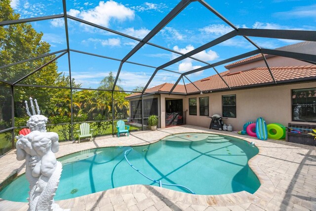 view of pool with a patio area and glass enclosure