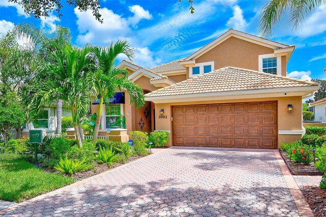 view of front facade with a tile roof, decorative driveway, a garage, and stucco siding