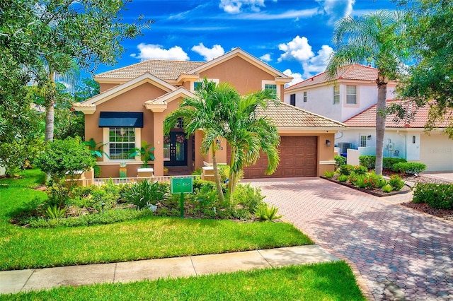 mediterranean / spanish home featuring a tiled roof, decorative driveway, a garage, and stucco siding