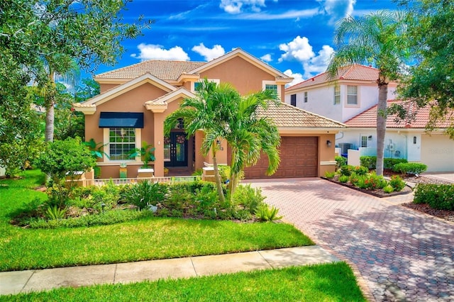 mediterranean / spanish home featuring driveway, an attached garage, stucco siding, a front lawn, and a tile roof