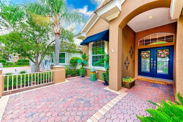 doorway to property featuring stucco siding, a tile roof, and french doors