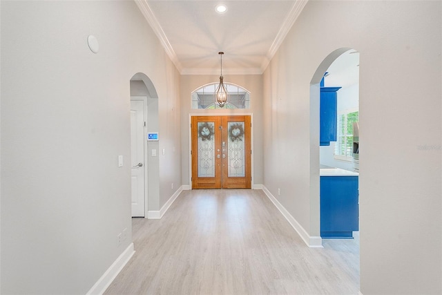 entrance foyer featuring arched walkways, light wood finished floors, and ornamental molding