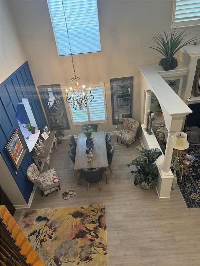 living room featuring an inviting chandelier, wood finished floors, and a towering ceiling