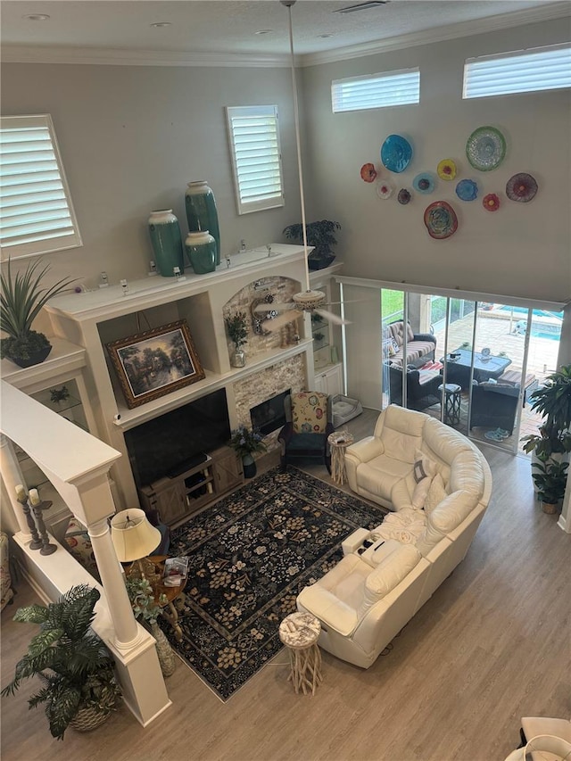 living area with a glass covered fireplace, crown molding, and wood finished floors