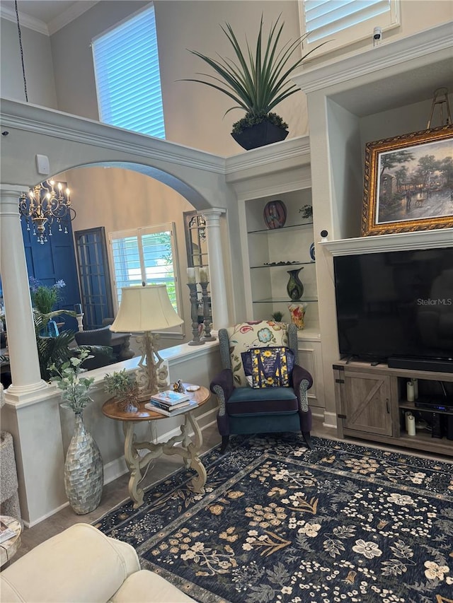 living room with ornamental molding, decorative columns, a towering ceiling, arched walkways, and a notable chandelier